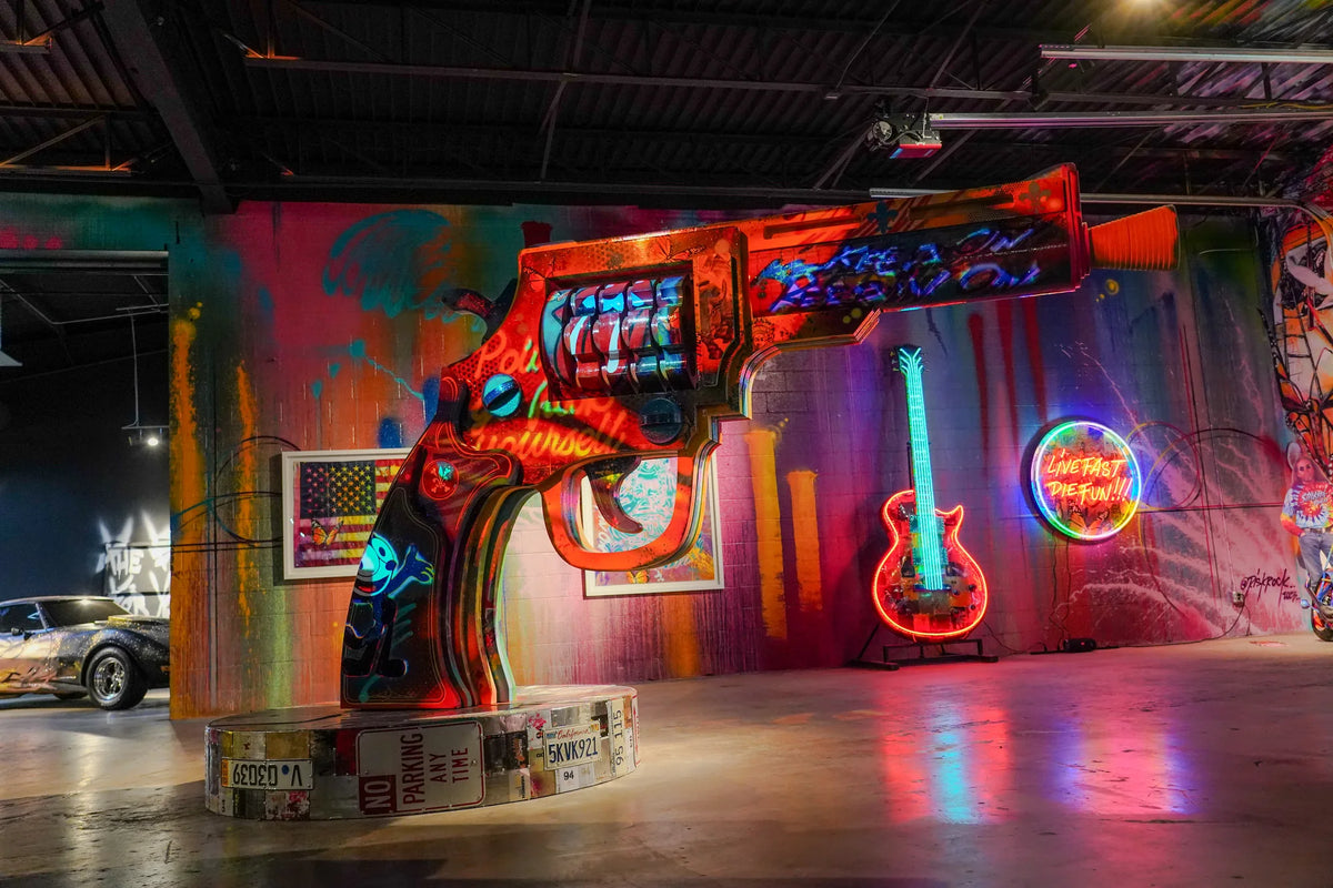 Large painted revolver sculpture and neon guitar inside Gallery DeFi